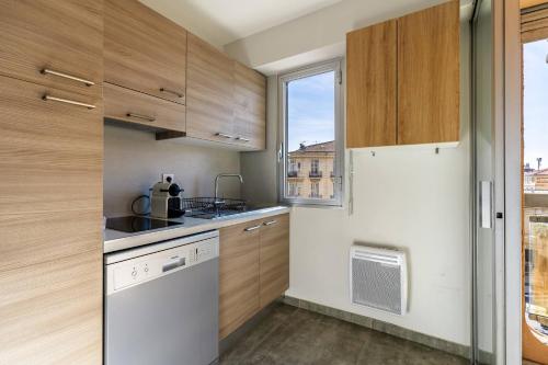 Elle comprend une petite cuisine avec des placards en bois et une fenêtre. dans l'établissement Jolie studio avec belle terrasse ensoleillee, à Nice