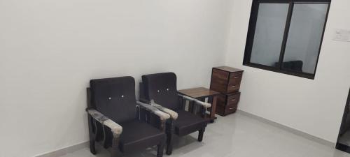 two chairs in a room with a mirror and a dresser at Madhav NATH Homestay in Garudeshwar