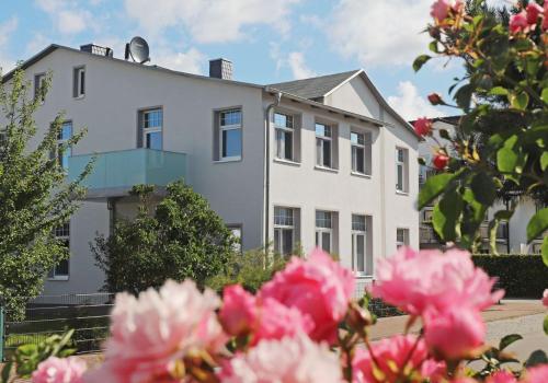 a white house with pink flowers in front of it at Haus Seestern in Thiessow