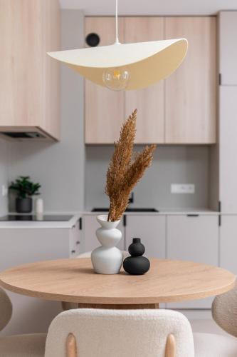 a dining room table with a vase and a lamp at Sandstone Apartament - homfi Collection in Kraków