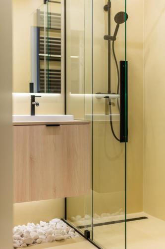 a shower with a glass door and a sink at Sandstone Apartament - homfi Collection in Kraków