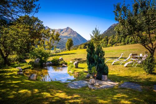 a pond in a field with a picnic table and mountains at Dorfergut in Weisspriach