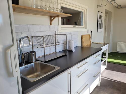 a kitchen with a sink and a black counter top at Halmstad Golfarena stugor in Halmstad
