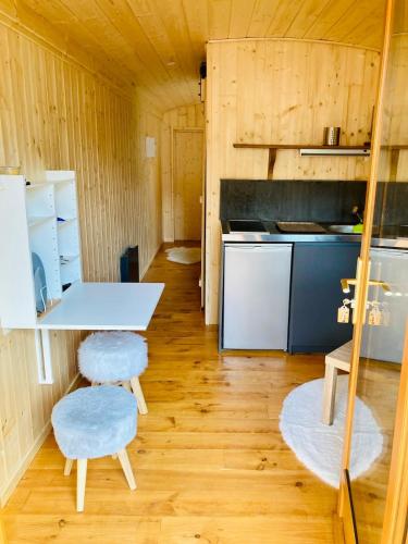 - une cuisine avec une table et deux tabourets dans une pièce dans l'établissement Roulotte atypique à l'Océan, à Labenne