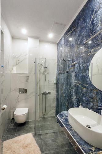 a bathroom with a glass shower and a sink at Klimt's Puzzle Suite in Sofia