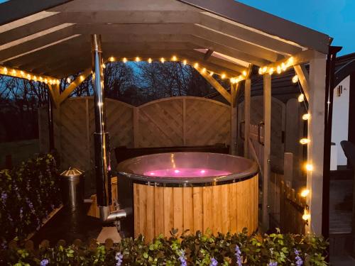 a hot tub under a pergola with lights at Cherry Pod in Shrewsbury