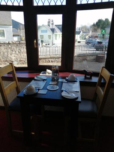 a table with plates and bowls on it in front of windows at Celicall in Ballater