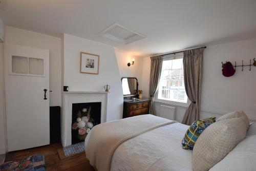 ein weißes Schlafzimmer mit einem Bett und einem Kamin in der Unterkunft Mim's Cottage in Rye