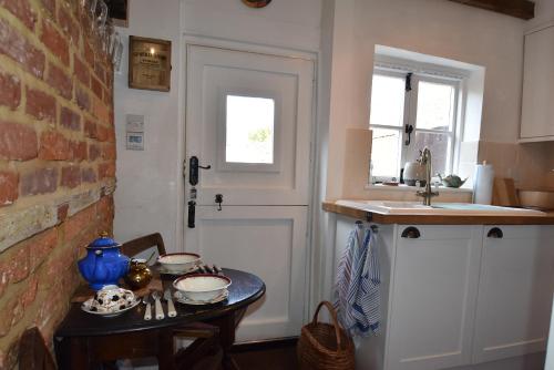 eine Küche mit einem Tisch und einer Spüle und einer Tür in der Unterkunft Mim's Cottage in Rye