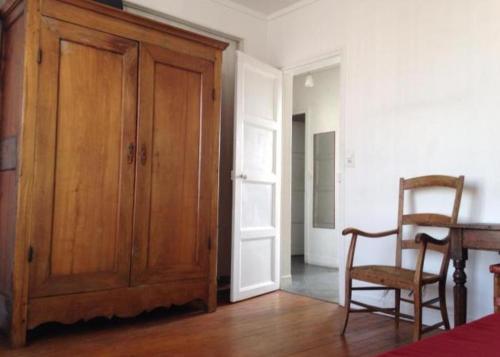 a room with a wooden cabinet and a table and a chair at Chambre chez l'habitant dans un appartement à 2 pas de la gare SNCF et à 300m de la gare routière in Creil