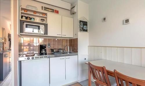 une cuisine avec des armoires blanches, une table et un micro-ondes dans l'établissement Studio 100 m de la plage, 5 minutes du centre ville, à Arcachon