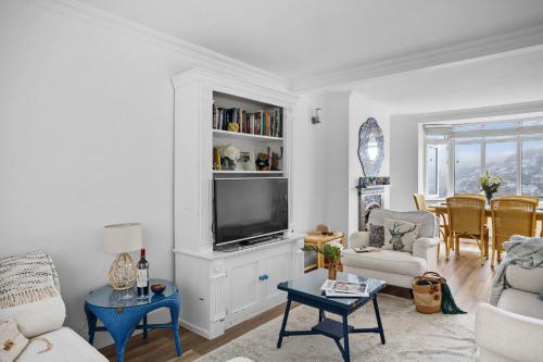 a living room with a tv on a cabinet at Uphigh - Elevated Family Home with Stunning River Views in Dartmouth