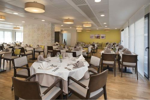 a dining room with white tables and chairs at DOMITYS - Le Pupitre d'Or in Saint-James