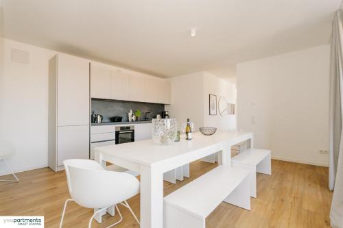 eine weiße Küche mit einem weißen Esstisch und Stühlen in der Unterkunft 139 QM - Exklusiv auf 2 Etagen - Werse Loft by youpartments in Münster