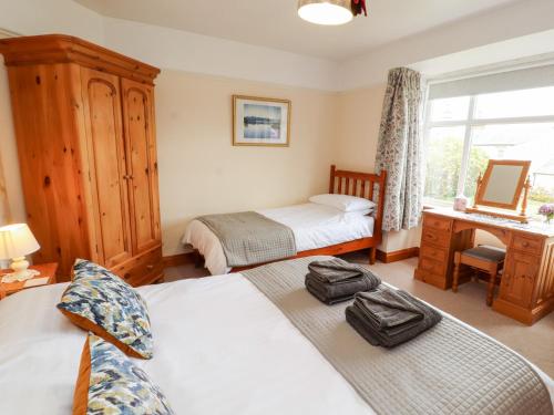 a bedroom with two beds and a desk with a mirror at Eusebank in Pooley Bridge