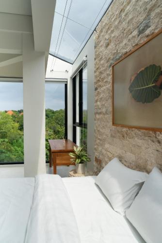 a bedroom with a white bed and a stone wall at UMI Luxury Villas Uluwatu Beach in Uluwatu
