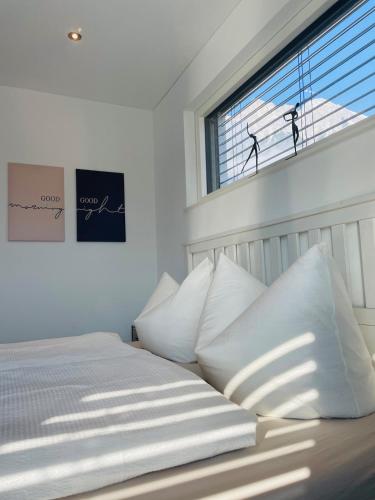 a bedroom with a bed with white pillows and a window at Inntal Alpin Apartments - Hohe Munde in Telfs