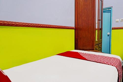 a bedroom with a bed with a green and yellow wall at Hotel O Noril Haromain Homestay Syariah in Pasuruan