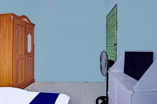 een slaapkamer met een bed, een dressoir en een deur bij SPOT ON 91918 Najla Guest House Syariah in Parit