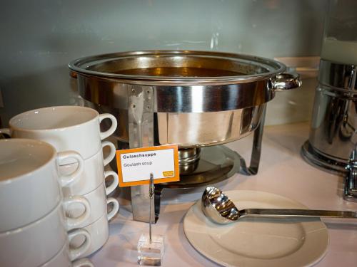 a pot on a counter with two cups and a spoon at Simm's Hotel - cityhotel next to Metro U3 in Vienna