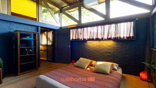 a bedroom with a bed and a brick wall at Chale na Mata Atlantica com rio e imersao natural in Garuva