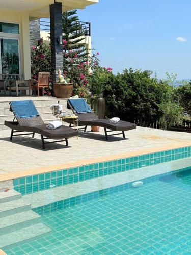 a swimming pool with two lounge chairs next to a house at Sea View Luxury Mansion, Pool & Jacuzzi - Koh Chang in Ko Chang