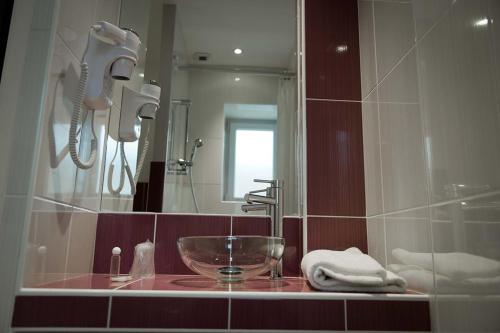 a bathroom with a sink and a mirror at Hôtel Montchapet Dijon Centre in Dijon