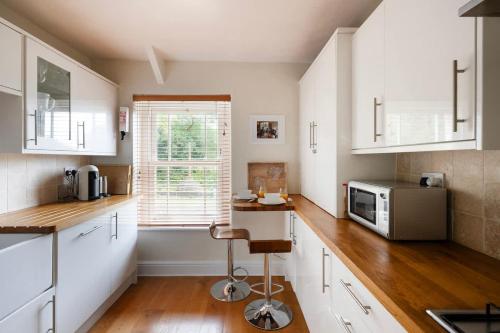 a kitchen with white cabinets and a microwave at The Mews Flat, near Clifton Suspension Bridge with off-street parking in Bristol