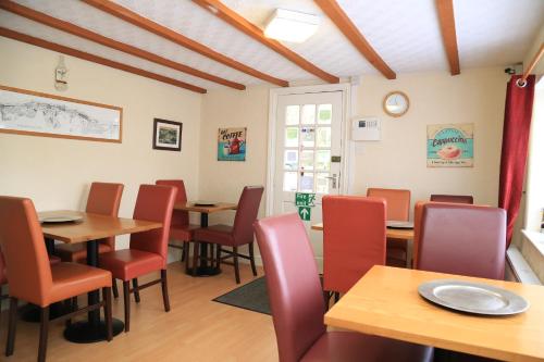 a dining room with wooden tables and red chairs at Ladywood House Bed and Breakfast in Ironbridge