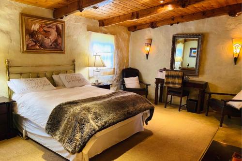 a bedroom with a bed and a desk and a mirror at Stonehaven Cottage in Machadodorp
