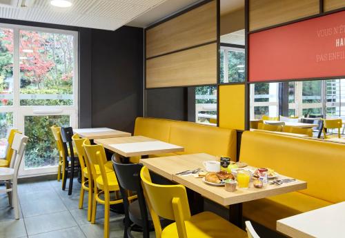 une salle à manger avec des tables et des chaises jaunes dans l'établissement B&B HOTEL Evry Lisses 2, à Lisses