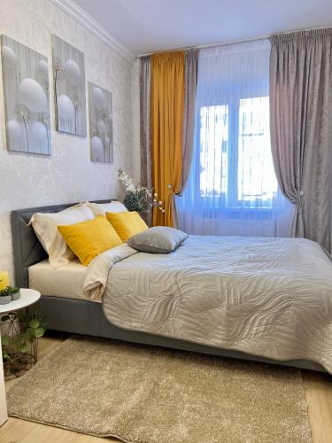 a bedroom with a bed with yellow pillows and a window at Квартира подобово Центр Руська in Ternopilʼ