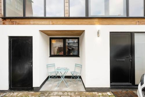 Dos sillas y una mesa frente a un edificio. en The Upside Down Eco House - Free parking with no height restrictions, en Bristol
