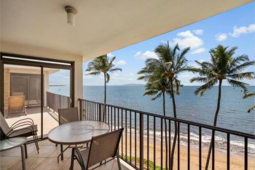 a balcony with a table and chairs and the ocean at Kihei Beach, #603^ condo in Kihei