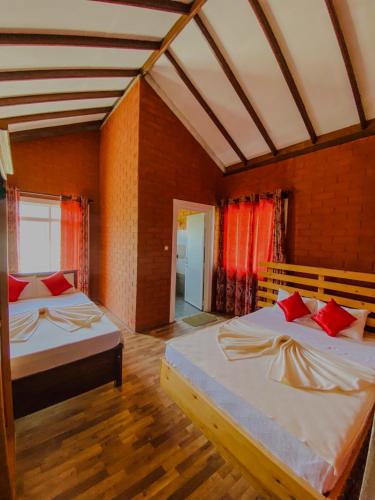 a bedroom with two beds with red pillows at Pearl Shine Bungalow Nuwaraeliya in Nuwara Eliya