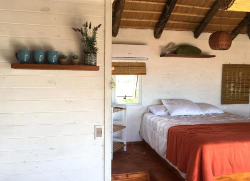 a bedroom with a bed and a window in a room at Cabañas Punta Papaya in Punta Del Diablo