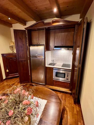 a kitchen with wooden cabinets and a table with roses at Apartment Manzoni Bardolino Center in Bardolino