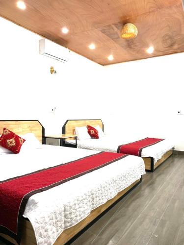 two beds in a hotel room with red and white sheets at Kien Trang 2 Homestay in Xuân Sơn