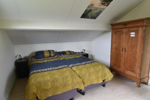 a bedroom with a bed and a wooden cabinet at Vakantiehuis Weids uitzicht nabij Tjeukemeer in Rohel