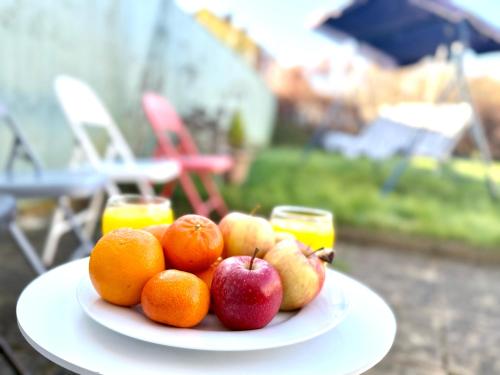 a plate of fruit on a table with oranges and apples at Stylish 3-Bedroom House with Garden & Free Parking's, Prime location with private garden in Kidlington