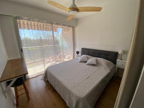 une chambre avec un lit et une grande fenêtre dans l'établissement Appartement lumineux et climatisé, face au parc privé et à 10 mins de la plage, à Cagnes-sur-Mer