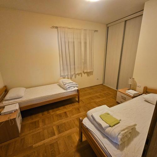 メジュゴリエにあるJudita Apartments & Roomsのベッドが2つと窓がある小さな部屋