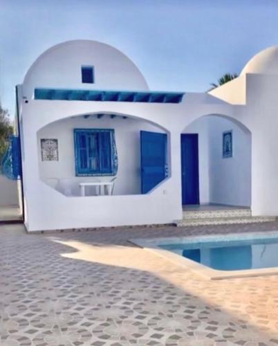 a white house with blue doors and a swimming pool at Villa Jasmin in Midoun