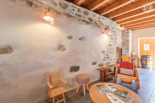 Cette chambre est dotée d'un mur en pierre avec des chaises et une table. dans l'établissement L'ours, à Montricher-Albanne