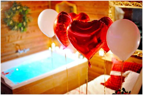 - un bouquet de ballons rouges et blancs à côté d'une baignoire dans l'établissement Le Chalet romantique, SPA XXL, Écran cinéma, Lit king size, cascade d'eau, à Bourgoin-Jallieu