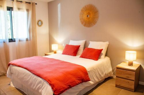 une chambre avec un grand lit avec deux oreillers rouges dans l'établissement Casa Cavu di Santa Lucia, à Sainte-Lucie de Porto-Vecchio