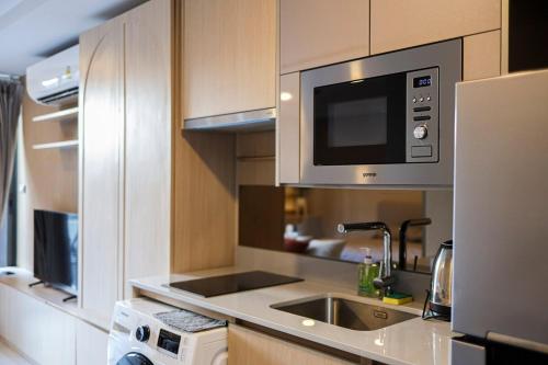 una cocina con fregadero y microondas en The Estates In Walden BTS Asoke, en Bangkok