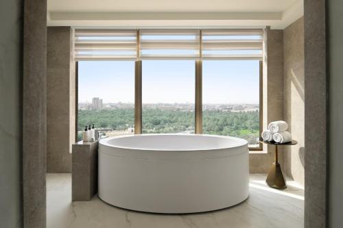 a bathroom with a tub in front of a large window at Al Ahsa InterContinental by IHG in Al Ahsa