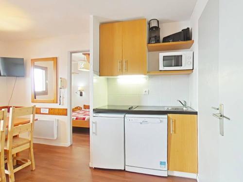 La cuisine est équipée d'un réfrigérateur blanc et d'un four micro-ondes. dans l'établissement Appartement 2 pièces au pied des pistes avec casier à ski et WiFi - FR-1-351-198, à La Plagne Tarentaise
