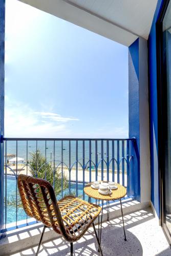 a balcony with a table and a chair and the ocean at LCV Mũi Né Resort in Mui Ne